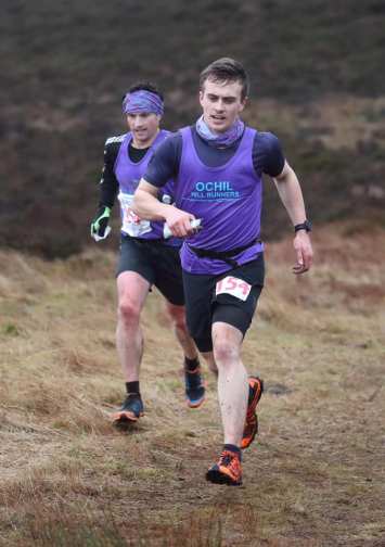 Two hill runners running side-by-side in purple vests