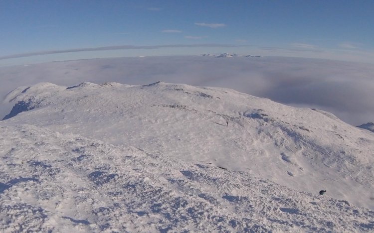 Blue skies, a sea of cloud and snow capped mountains emerging