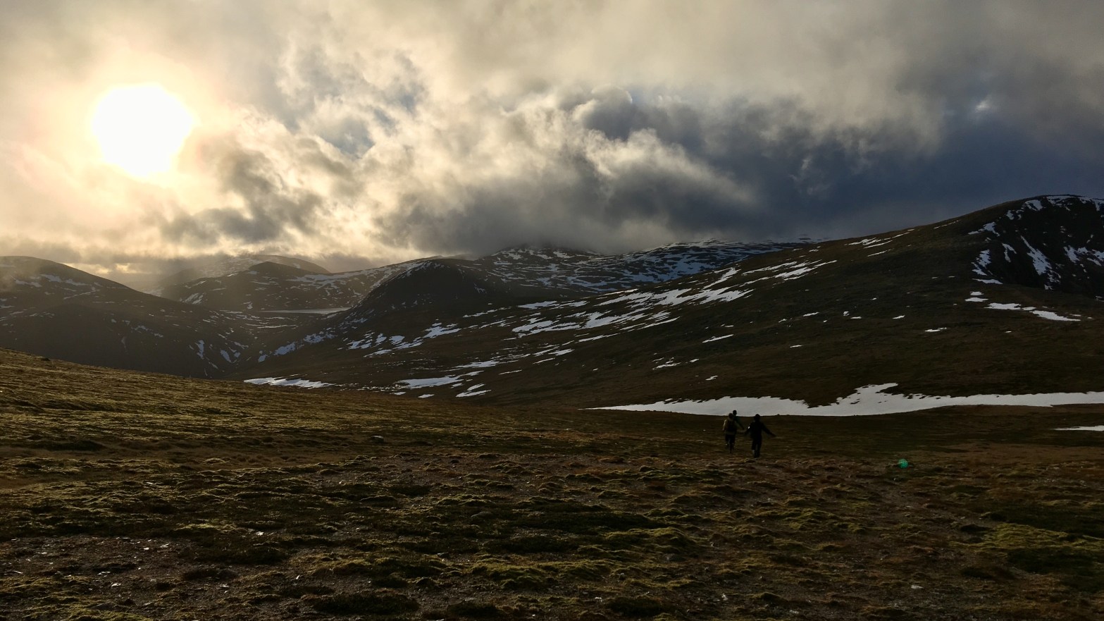 Three runners running into the sun in mountains