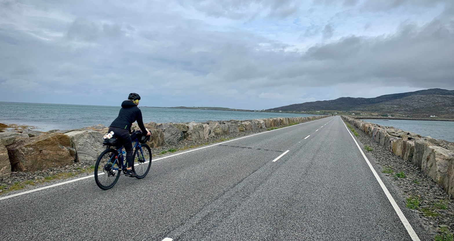 Cyclist on a causeway over the sea.